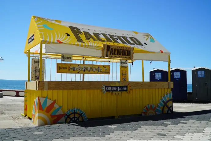 Barra simple amarilla de Cerveza Pacífico frente al mar durante el Carnaval de Mazatlán.
