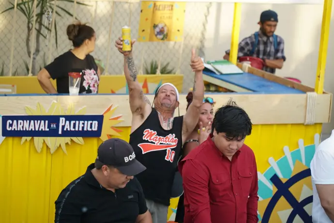 Barra simple de Cerveza Pacífico con personas disfrutando del momento en el Carnaval de Mazatlán 2026.