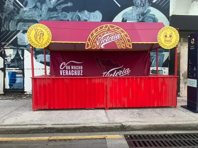 Barra sencilla de Cerveza Victoria instalada por Entorno Lab durante el Carnaval de Veracruz 2025, con identidad de marca y atención al público asistente.