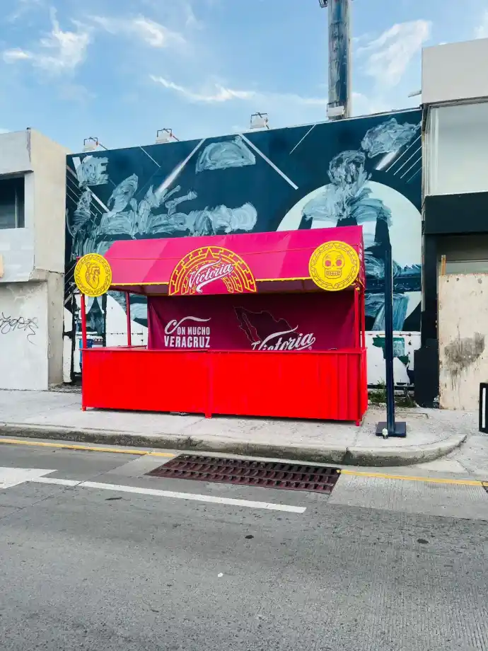 Barra sencilla de Cerveza Victoria instalada por Entorno Lab durante el Carnaval de Veracruz 2025, con identidad de marca y atención al público asistente.