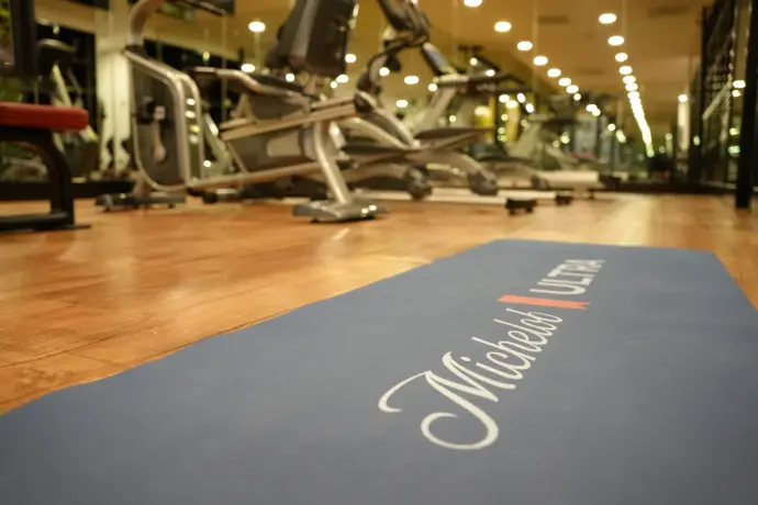 Tapete de yoga Michelob Ultra en gimnasio Tapete de yoga con logo Michelob Ultra sobre piso de madera en gimnasio de hotel, parte del takeover Mundial 2026