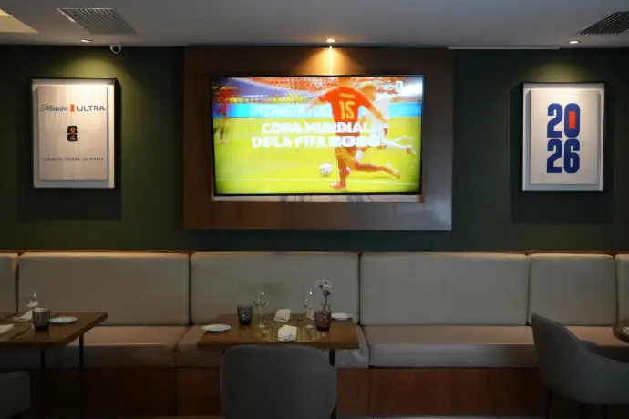 Michelob Ultra transmisión partido Mundial FIFA 2026 Televisión mostrando "Copa Mundial de la FIFA 2026" en área de restaurante con branding Michelob Ultra en la pared