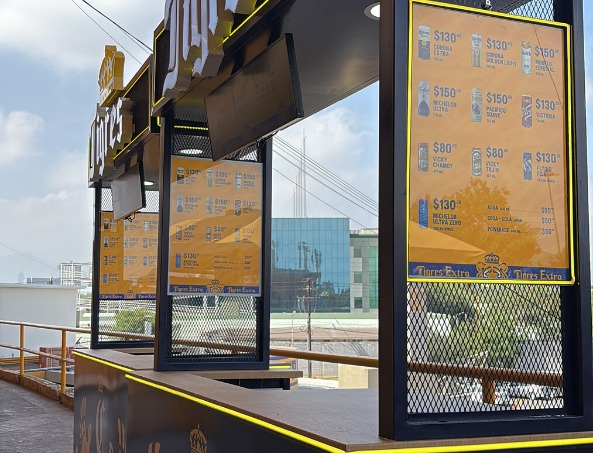 Detalle de menús y estructura de los carritos Tigres Extra Detalle de los paneles de menú retroiluminados con precios y portafolio Tigres Extra, integrados a la estructura metálica con malla expandida y cubierta de madera del carrito.